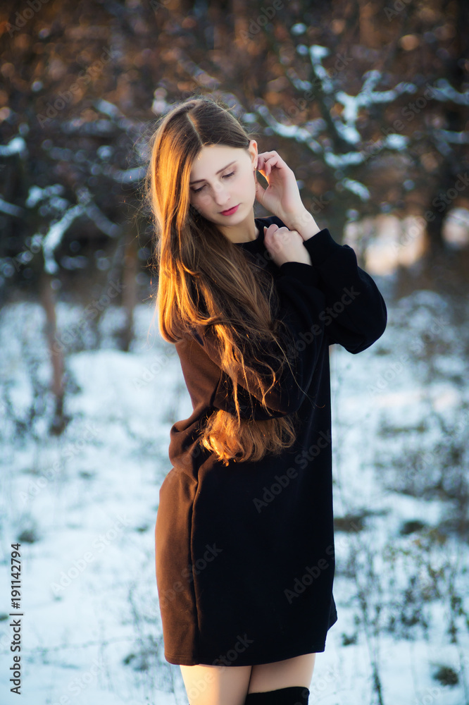 A fashion model in a black dress in the winter in the yard puts on a photo shoot A fashion model in a black dress in the winter in the yard puts on a photo shoot