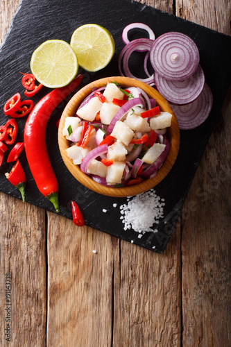 Healthy fish ceviche of cod with onion and pepper close-up on a plate. Vertical top view