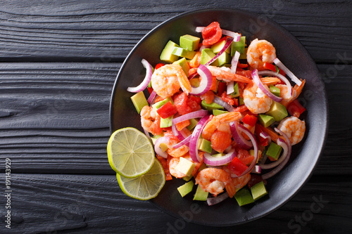Delicious ceviche of shrimp with vegetables, spices and lime close up on a plate. horizontal top view