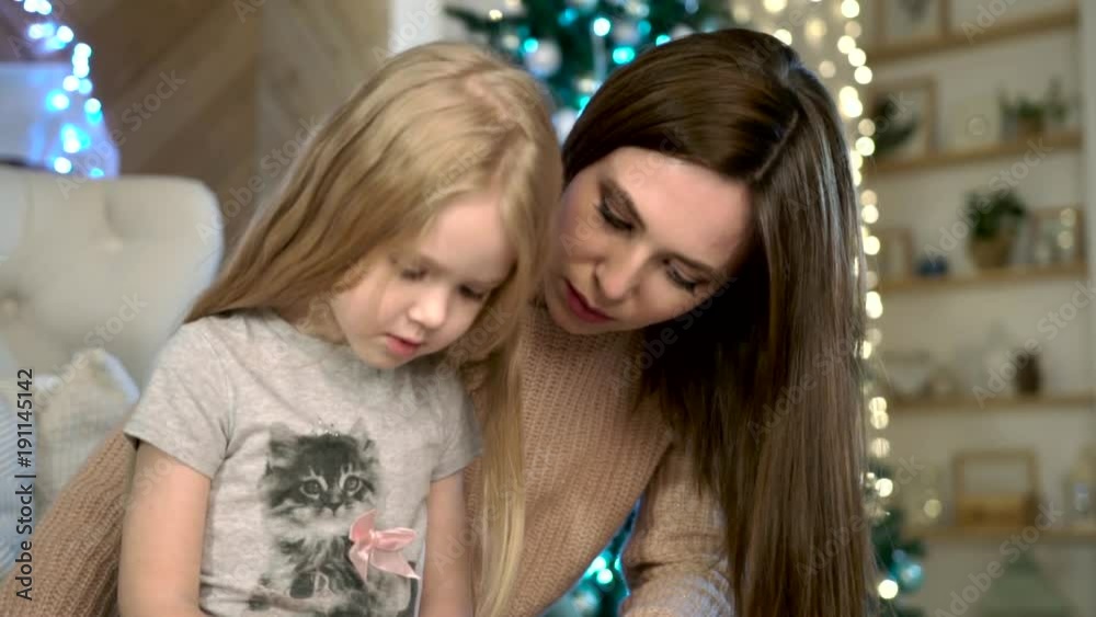 Mother plays with child. Mom and daughter. Mother teaches daughter to write. Write a letter to Santa Claus. Mother plays with child. Mom and daughter. Mother teaches daughter to write. Write a letter to Santa Claus.
