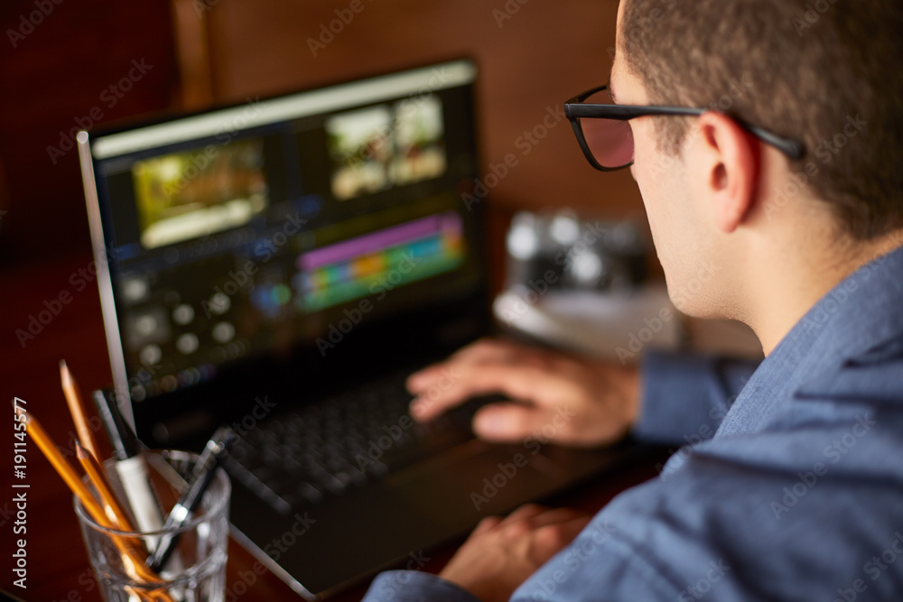 Freelancer video editor works at the laptop computer with movie editing sofware. Videographer vlogger or blogger camera man at work editing vlog. Tracking and revealing shot Freelancer video editor works at the laptop computer with movie editing sofware. Videographer vlogger or blogger camera man at work editing vlog. Tracking and revealing shot