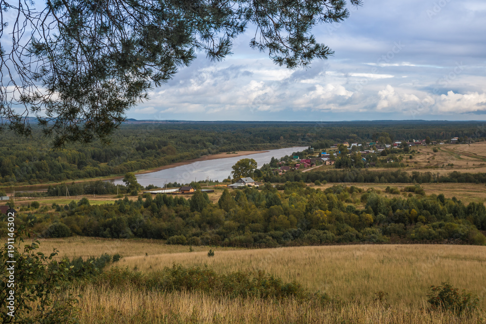 Fototapeta premium View from the height on the field, trees and river in the distance in autumn day