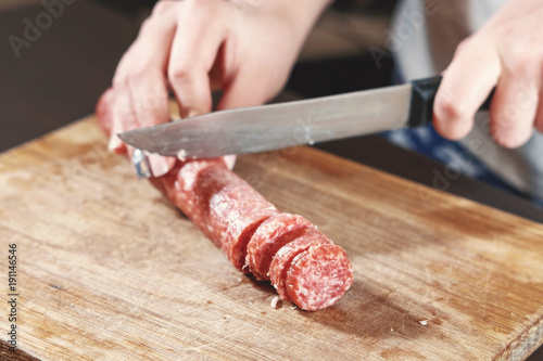 sausage, knife, hands of woman, slicing sausage, thick pieces, wooden plank, knife in female hands, woman cuts the sausage
