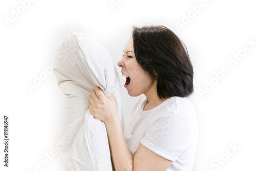 angry woman with insomnia yelling and holding pillows while sitting in bed photo