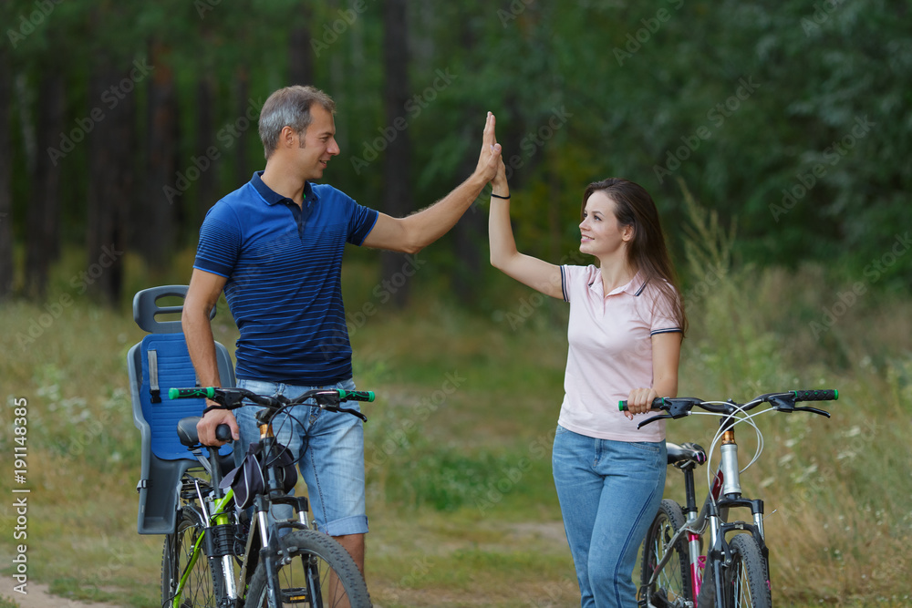 Obraz premium Happy couple with bikes funs in pine forest