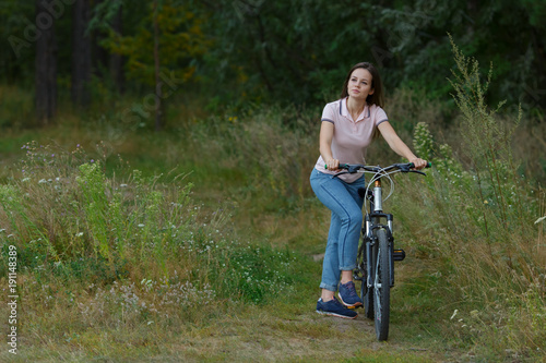 Happy beautiful girl riding on bicycle in the forest.