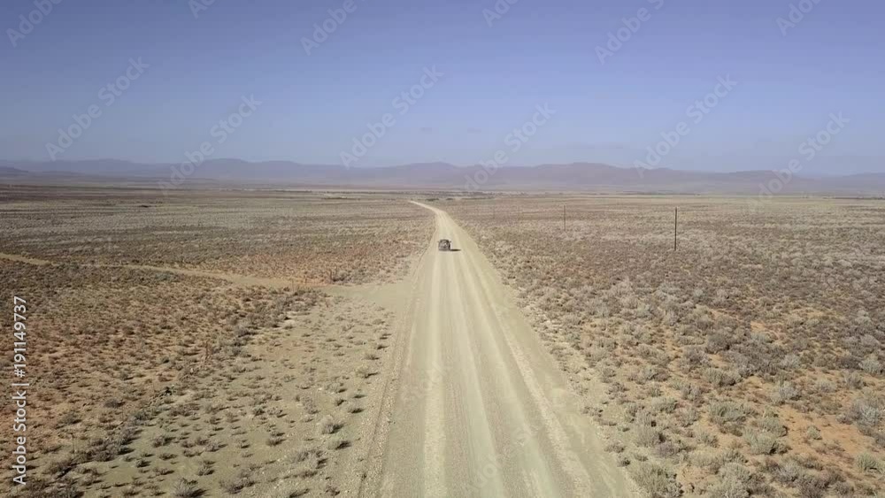Aerial of SUV traveling along a dusty dirt road in semi-arid desert. Aerial of SUV traveling along a dusty dirt road in semi-arid desert.