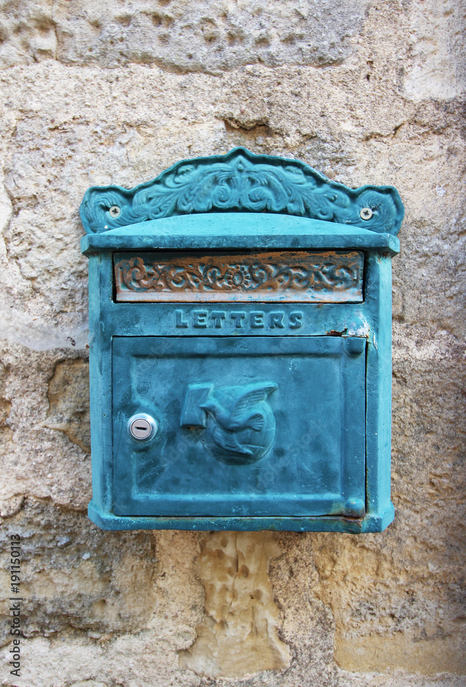 Old blue metal letterbox on stone wall