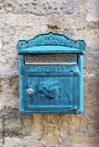 Old blue metal letterbox on stone wall