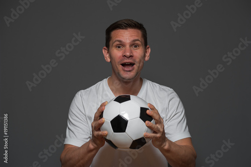 Portrait of young excited man soccer or football fan holding ball in hand © pavel_shishkin