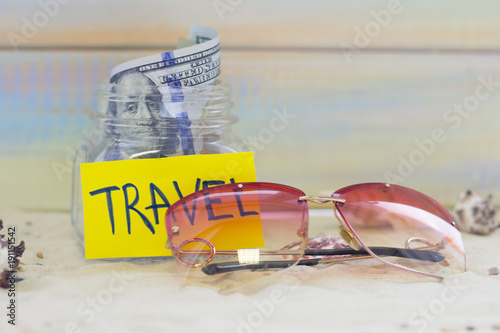 Planning for vacation, saving money for next trip. Sunglasses on sand background photo