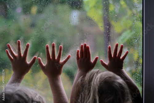 children near the glass in the rain