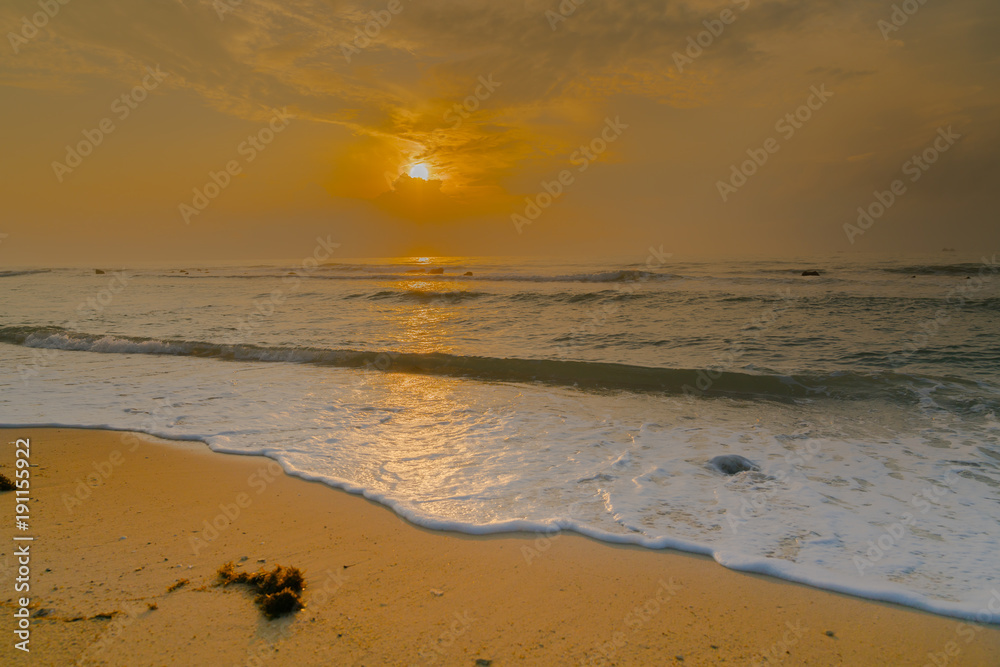 Golden Sunrise and glistening white sea foam on shore at Koh Samui