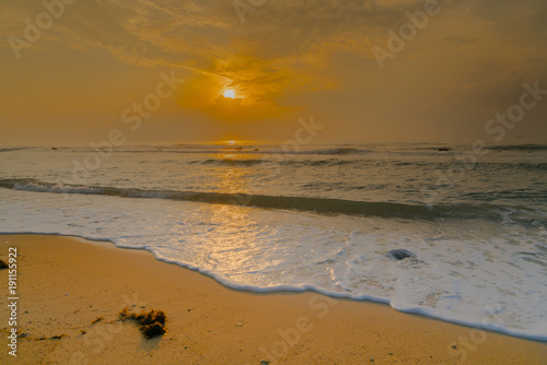 Golden Sunrise and glistening white sea foam on shore at Koh Samui