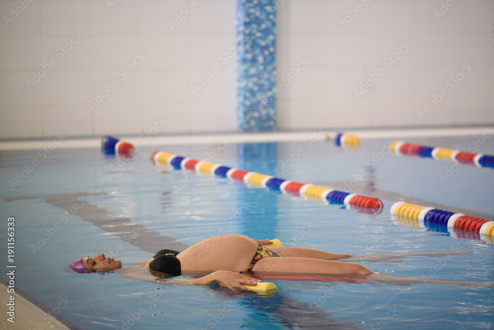 Water Yoga; a pregnant woman does her yoga exercises at the pool