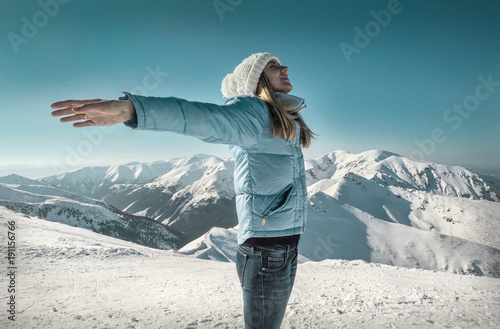 Happy woman relaxing on the top of mountain under blue sky with