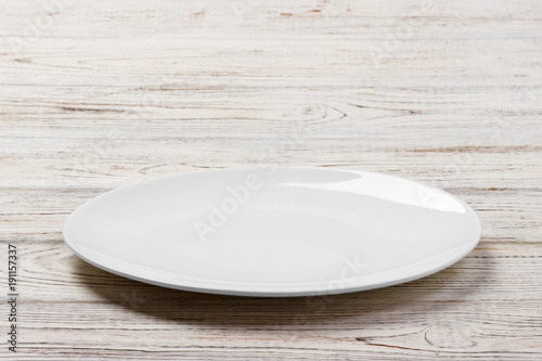 White Round Plate on white wooden table background. Perspective view