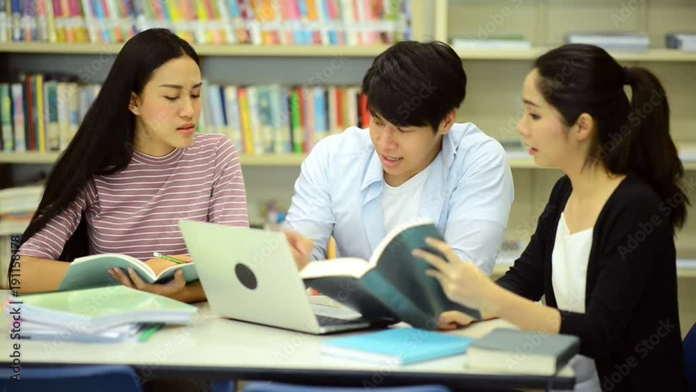 Young students study hard in library. Happy Asian female and male university students doing study research in library with books on desk, notebook. For back to school education diversity concept. Young students study hard in library. Happy Asian female and male university students doing study research in library with books on desk, notebook. For back to school education diversity concept.