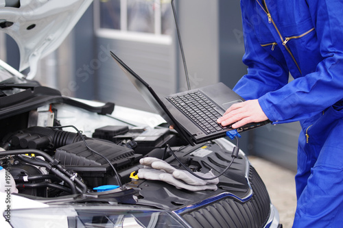 Mechaniker arbeitet mit einem Laptop an einem Auto, Motorsteuerung  photo