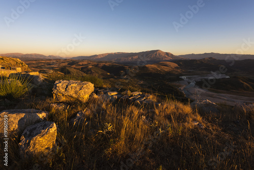 Sunset panorama taken from Byllis village - view of landscape with stones, river band and mountains in the background, Byllis, Fier Country, Albania, Europe