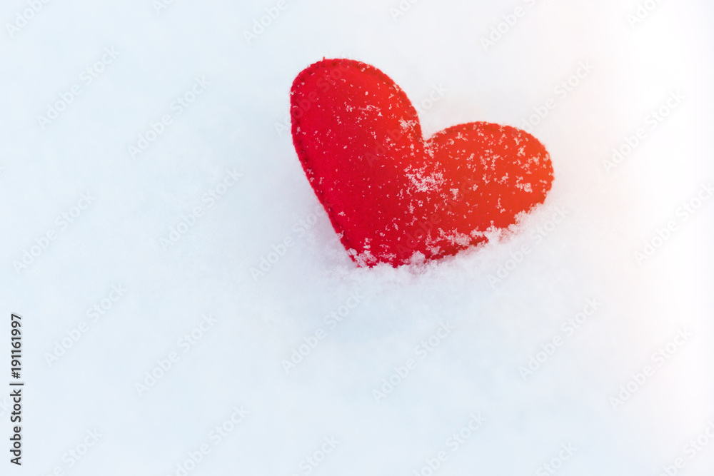 red felt heart figure on snow, winter day with sun glare