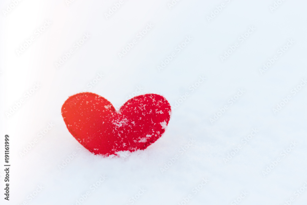 Fototapeta premium red felt heart figure on snow, winter day with sun glare