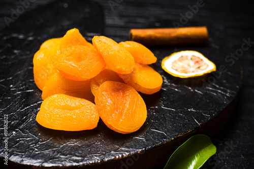 Dried apricot slices on a dark plate photo