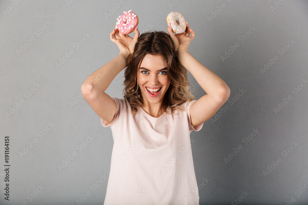 Happy woman in t-shirt having fun while holding donuts
