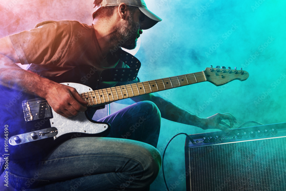 Naklejka premium The guitarist tunes the combo amplifier.