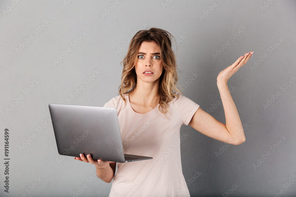 Confused woman in t-shirt holding laptop computer