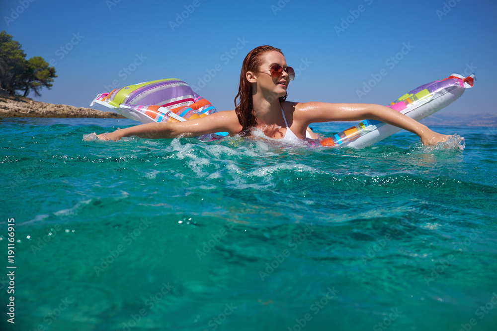 Happy woman in bikini lying on air bed in sea or ocean
