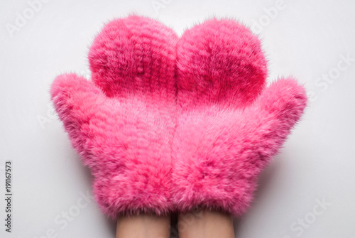Fluffy mittens. Close up part of woman hands in fluffy pink mittens against white background
