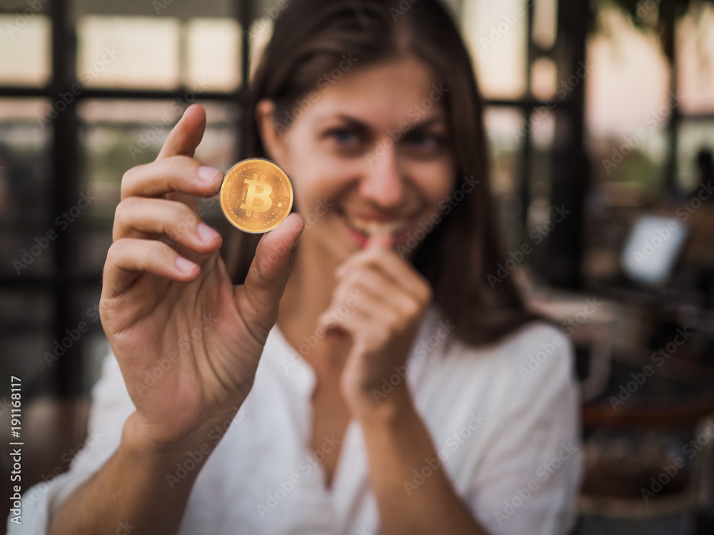 happy young investor woman holds bitcoin in her hand happy young investor woman holds bitcoin in her hand