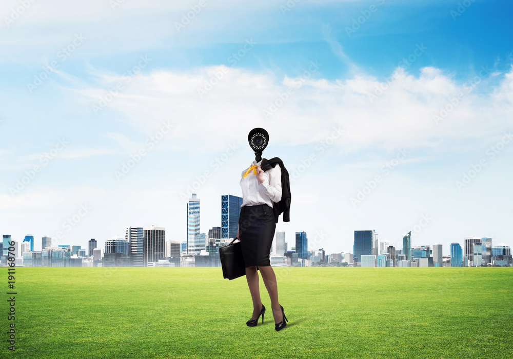 Camera headed woman standing on green grass against modern cityscape