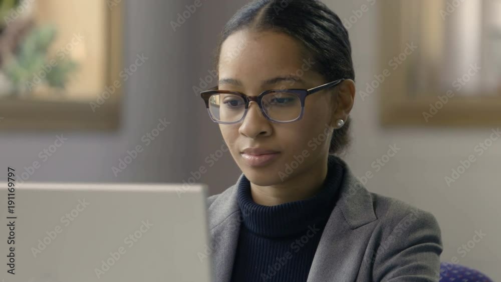 Young black female working at computer in a modern setting, close up