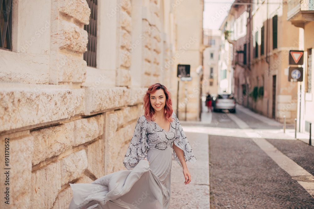smiling elegant girl in glamorous grey dress walking in Verona