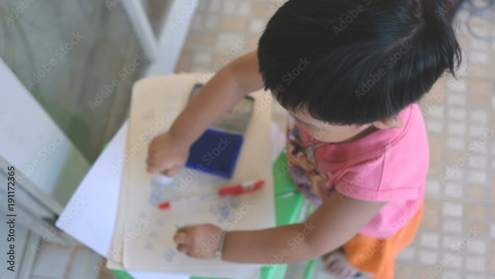 Little boy using stamper with blue ink and stamp on paper as artwork from high angle view. Selective focus Little boy using stamper with blue ink and stamp on paper as artwork from high angle view. Selective focus