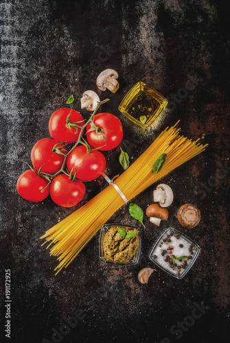 Food background, ingredients for cooking dinner. Pasta spaghetti, vegetables, sauces and spices,dark rusty background copy space top view