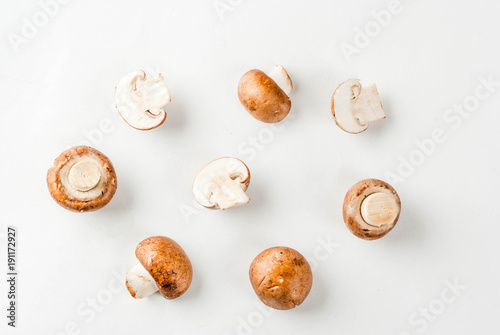 Fresh vegetables, raw whole and cut brown mushrooms, on white background, isolation copy space top view