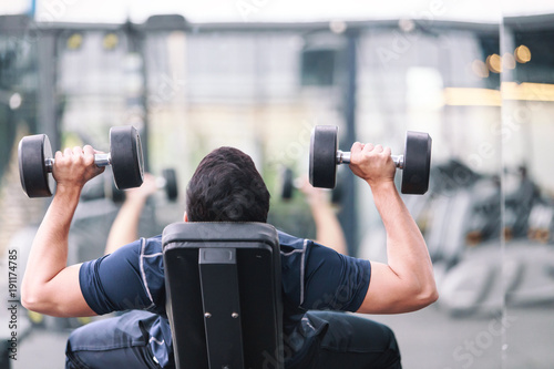 man exercising in fitness gym for good health. Athletic young man exercising equipment at gym, workout in fitness center.