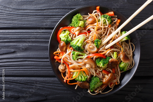 fried soba noodles with mushrooms, broccoli, carrots, peppers closeup on a plate. horizontal top view