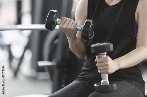 Woman exercising in fitness gym for good health. Athletic young woman exercising equipment at gym, workout in fitness center.
