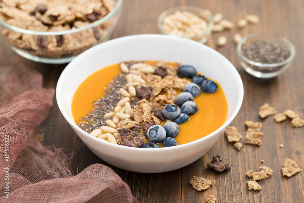 puree of mango with granola, chia and berries in white bowl puree of mango with granola, chia and berries in white bowl