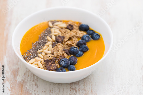 puree of mango with granola, chia and berries in white bowl