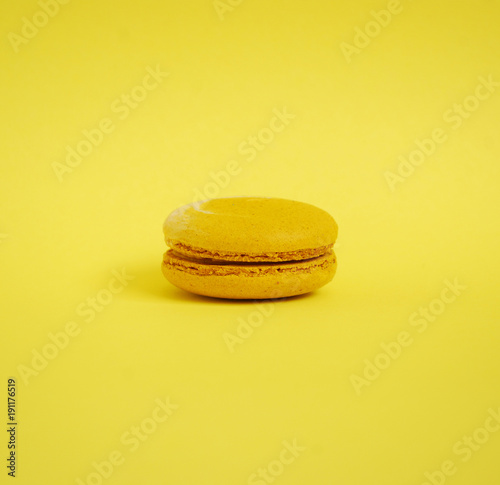 Yellow french sweet macaroon on pastel yellow background. Art food concept.