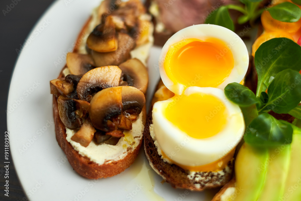 Bruschetta, assorted, different fillings, on plates with a soft-boiled egg in the middle Bruschetta, assorted, different fillings, on plates with a soft-boiled egg in the middle