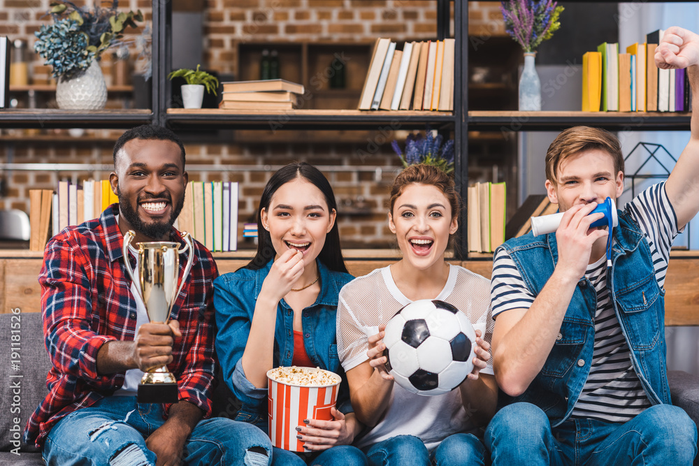 happy young multiethnic friends watching soccer match together at home