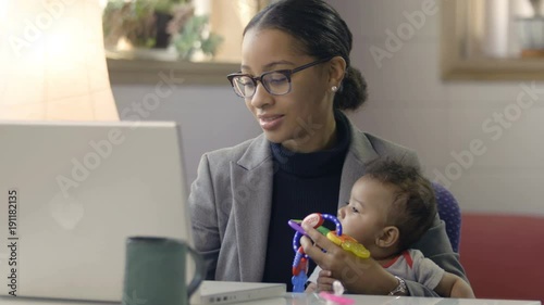 Mother holding baby and working at computer