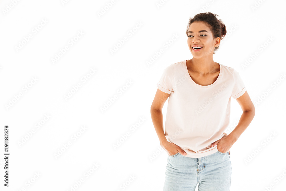Portrait of joyous african american woman smiling with hands in pockets and lookind aside on copyspace, isolated over white background Portrait of joyous african american woman smiling with hands in pockets and lookind aside on copyspace, isolated over white background