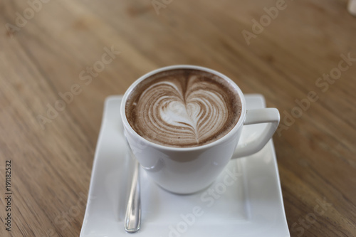 Top view cup of hot coffee latte art heart-shaped wooden floor.